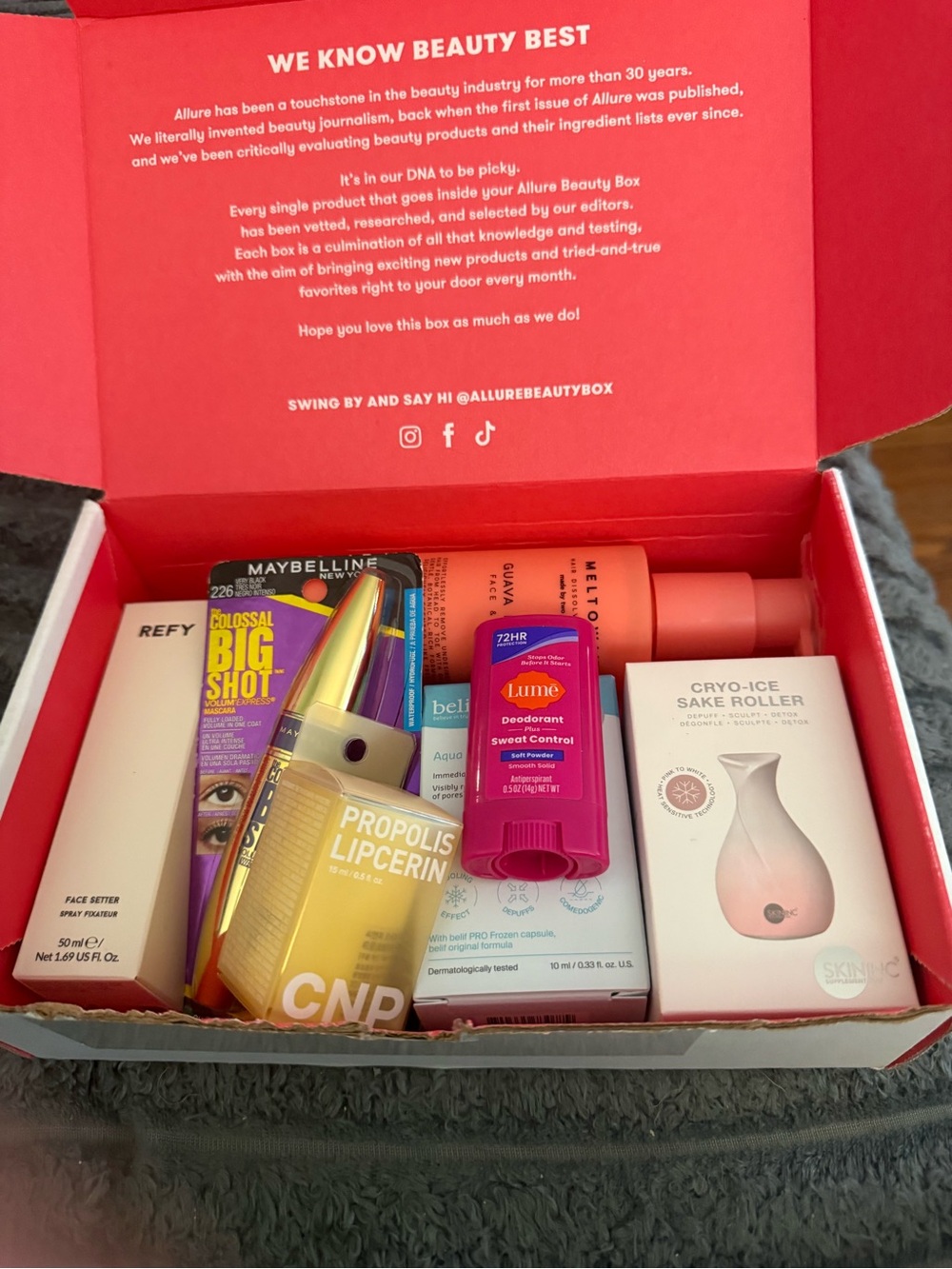 Allure beauty box with bright pink interior and mixed cosmetics plus Maybelline